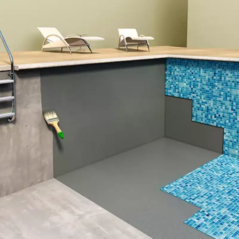 Piscina en construcción con paredes y fondo recubiertos con mortero elástico gris como base impermeabilizante, antes de la instalación de mosaicos azules. Se observa un cepillo, escaleras y tumbonas al fondo, indicando soluciones especializadas para clubes deportivos y casas.