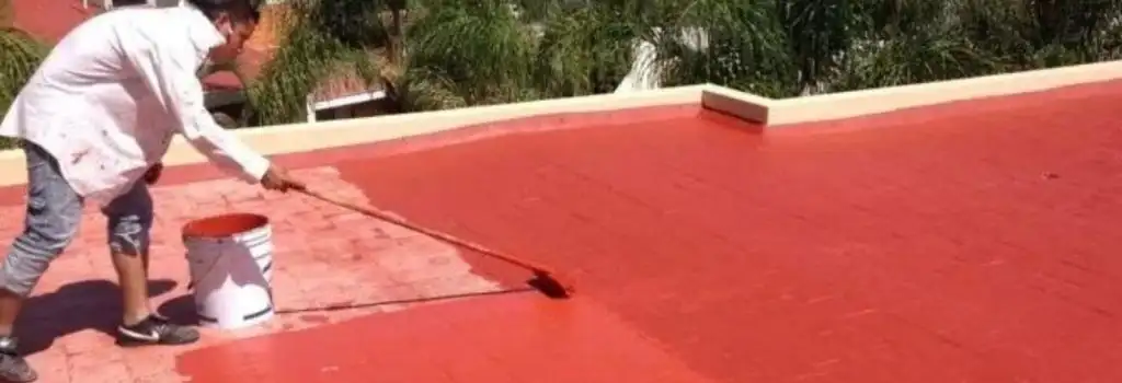 Técnico de Quantumef aplicando un recubrimiento impermeabilizante acrílico de color rojo sobre una azotea en la CDMX. La imagen soporta la promesa de 30 años de experiencia, eliminando filtraciones y humedad en alcaldías como Miguel Hidalgo y Benito Juárez.