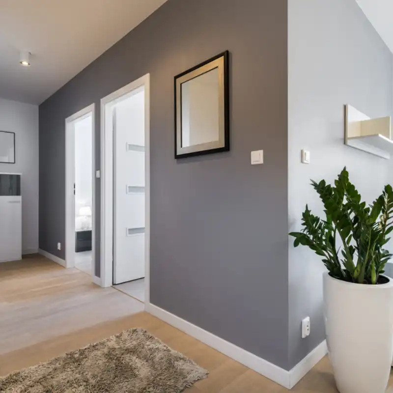 Interior de una casa en Huixquilucan, Estado de México, mostrando el acabado de pintura profesional en un pasillo con paredes grises y puertas blancas, como parte del servicio de remodelación residencial.