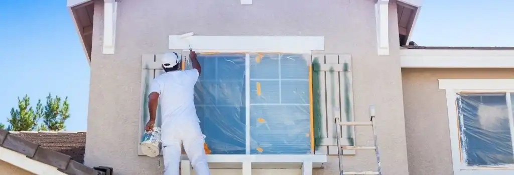 Pintor profesional de Quantumef aplicando pintura exterior en una casa de Huixquilucan, Estado de México, con protección de ventanas.