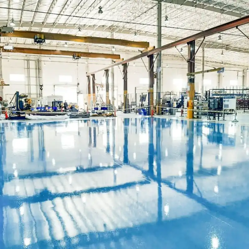 Interior de una nave industrial en Tlalnepantla, Estado de México, con pisos recubiertos de pintura epóxica azul de alto brillo y resistencia, ideal para tráfico pesado y químicos.