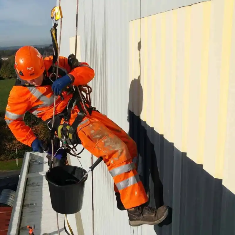 Pintor profesional de Quantumef con equipo de seguridad certificado realizando trabajos de altura (rappel) para pintar la fachada de un edificio corporativo en Naucalpan, Estado de México.