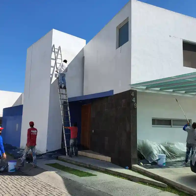 Equipo de pintores profesionales de Quantumef S.A. de C.V. realizando trabajos de pintura exterior en una casa residencial en la Ciudad de México, destacando el servicio de pintura de casas en Benito Juárez para máxima durabilidad.