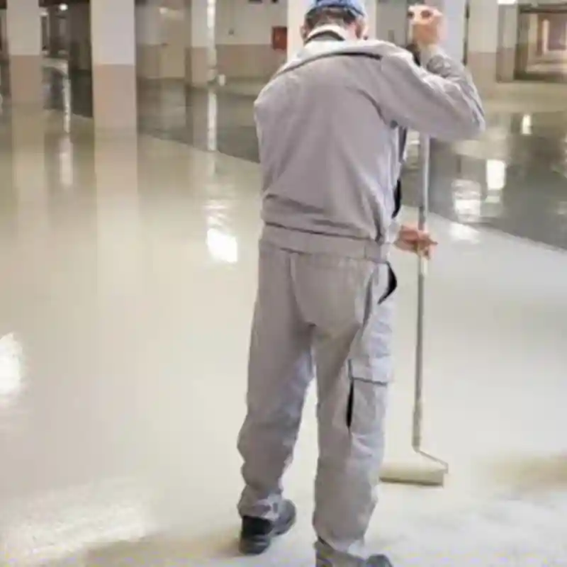 Trabajador de Quantumef S.A. de C.V. aplicando pintura epóxica de alta resistencia en el piso de una nave industrial, especializada para entornos de alto tráfico en zonas como Vallejo, CDMX.
