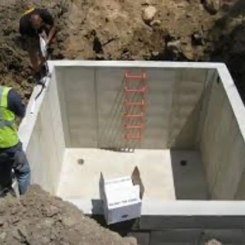 Obrero instalando recubrimiento cementoso blanco en las paredes de una cisterna de concreto recién construida. Este sistema resiste la presión hidrostática, garantizando la protección del agua potable en cisternas residenciales de Metepec y el Estado de México.